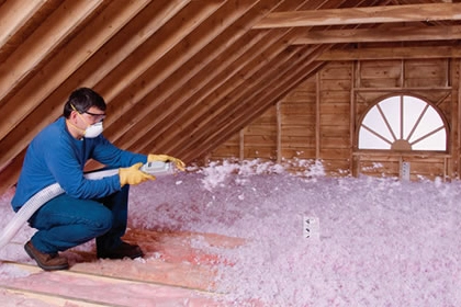 Technician installing blown-in insulation in attic space to improve home energy efficiency.