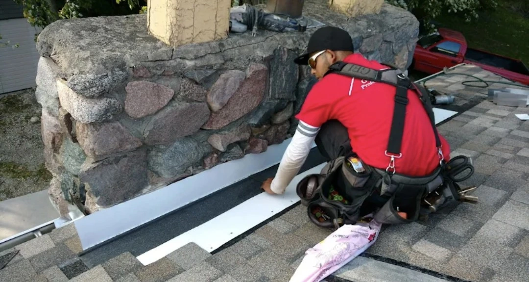 Roofing contractor installing flashing around a chimney during a residential roof repair.